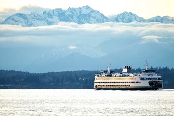 A large white boat is sailing on the water in front of a snowy mountain range  at Spyglass Hill Apartments, Bremerton, 98337